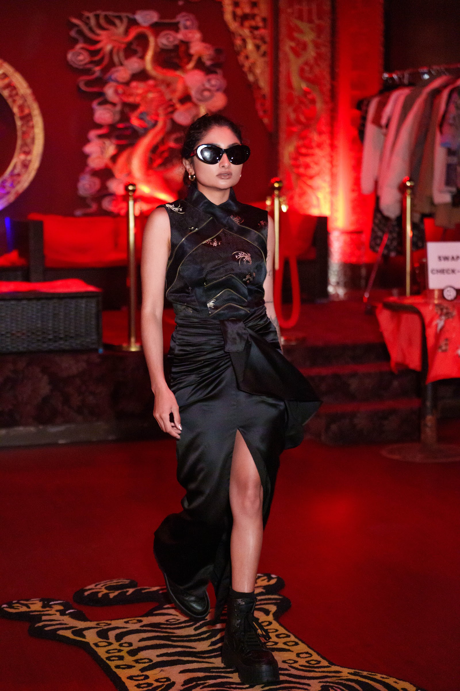 Model walking in a black look with red stage lighting
