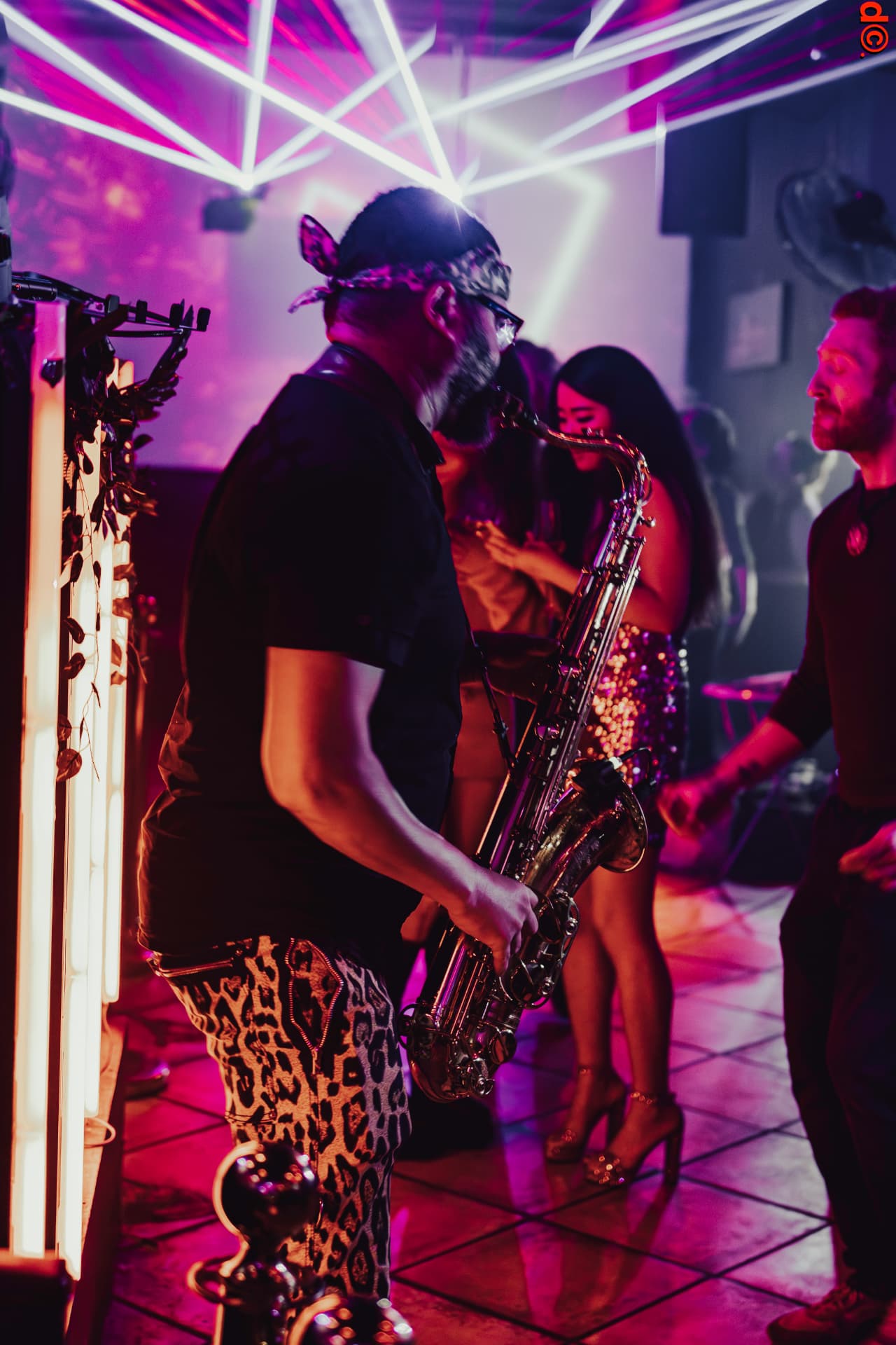 Saxophonist performing under laser lighting on the dance floor