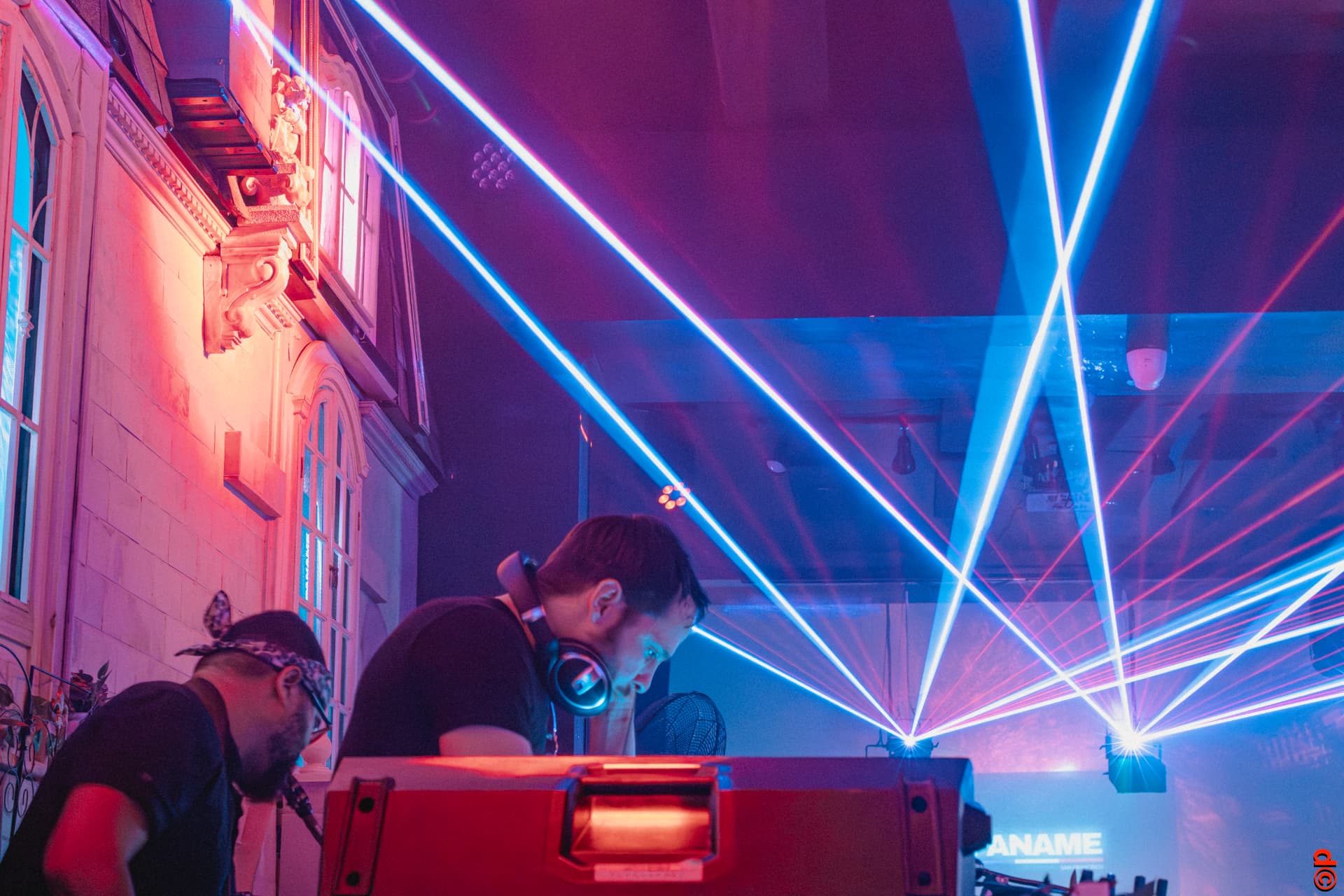DJs performing beneath sweeping blue and pink lasers